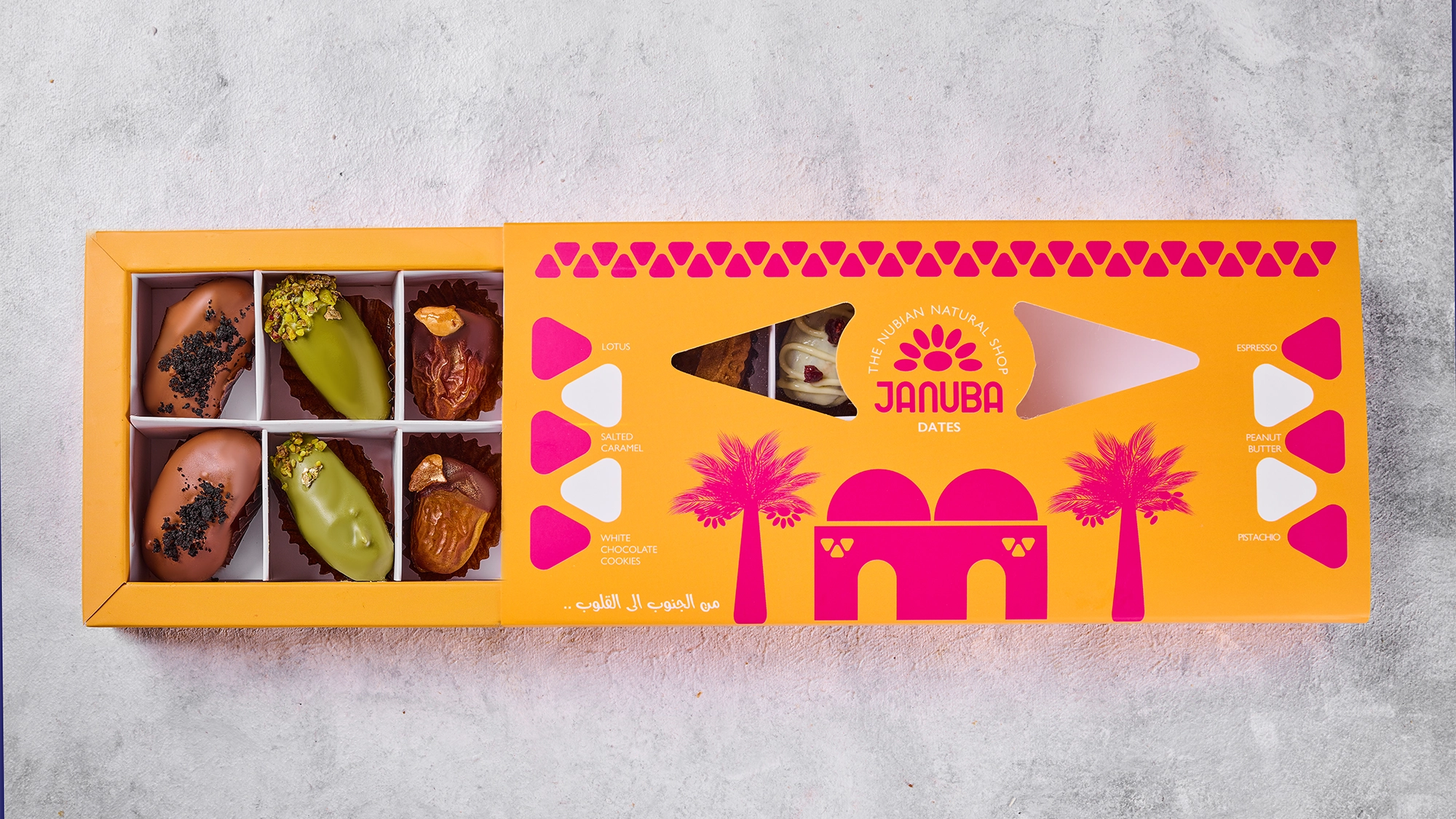 An open Januba box of assorted premium dates on a table set for Eid guests
