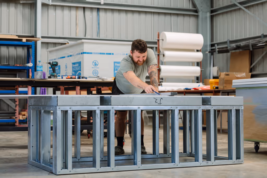 Star Baths male team member constructing a steel frame structure of a StarBath in their Raglan workshop.