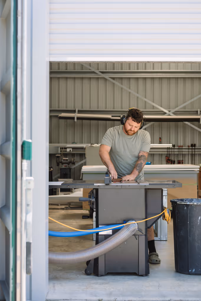 Star Baths craftsman cutting timber on a table saw in the Raglan workshop wearing ear protection