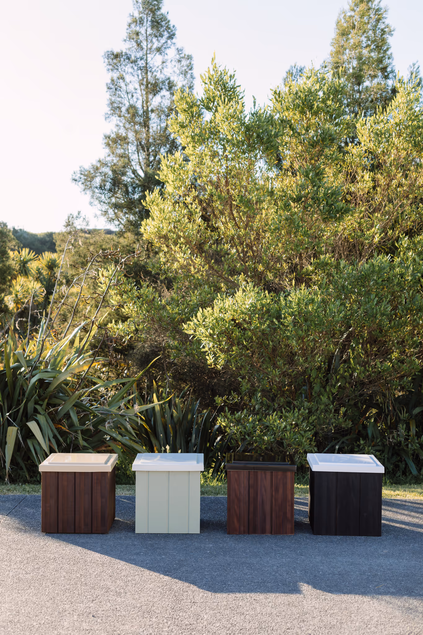 Range of Star Baths insulated storage boxes and bath seats in timber and painted finishes, displayed outdoors in a New Zealand garden setting