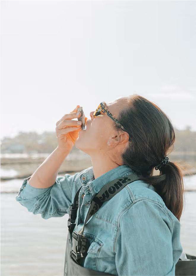 A women tilting her head back and eating an oyster