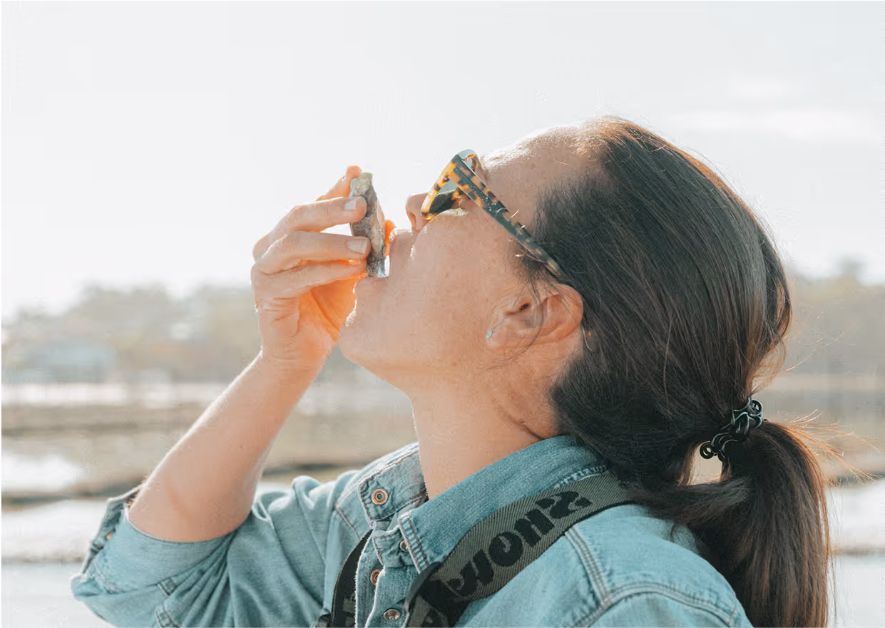 A women tilting her head back and eating an oyster