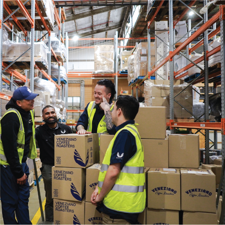 Veneziano Coffee Roasters team members sharing a candid moment outside their Richmond, Melbourne warehouse, standing and sitting by a branded delivery van.