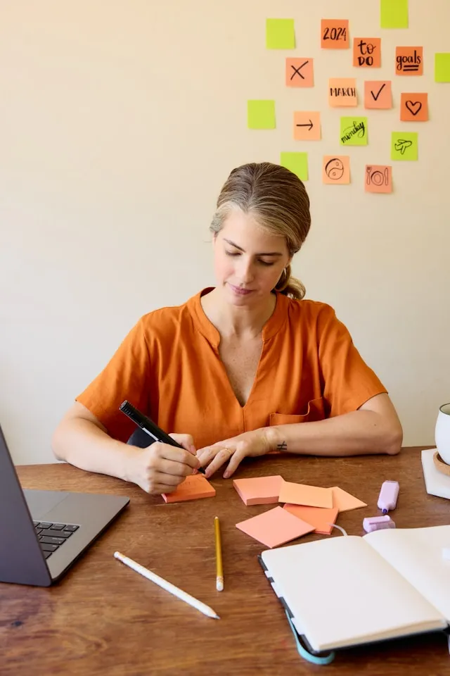A woman in a deep orange top sitting at her desk, undertaking the Future Women Leadership Program