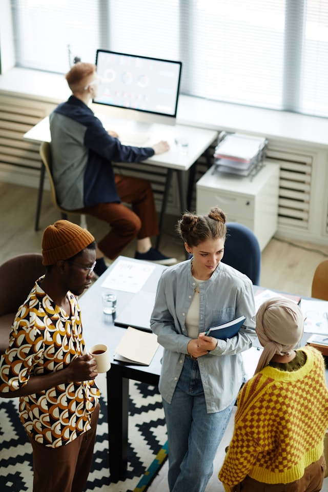 A group of team members standing around an office together, in a discussion about the frameworks and tools to stay grounded and effective under stress