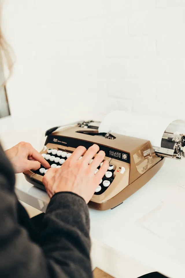 Hands typing at a traditional typewriter.