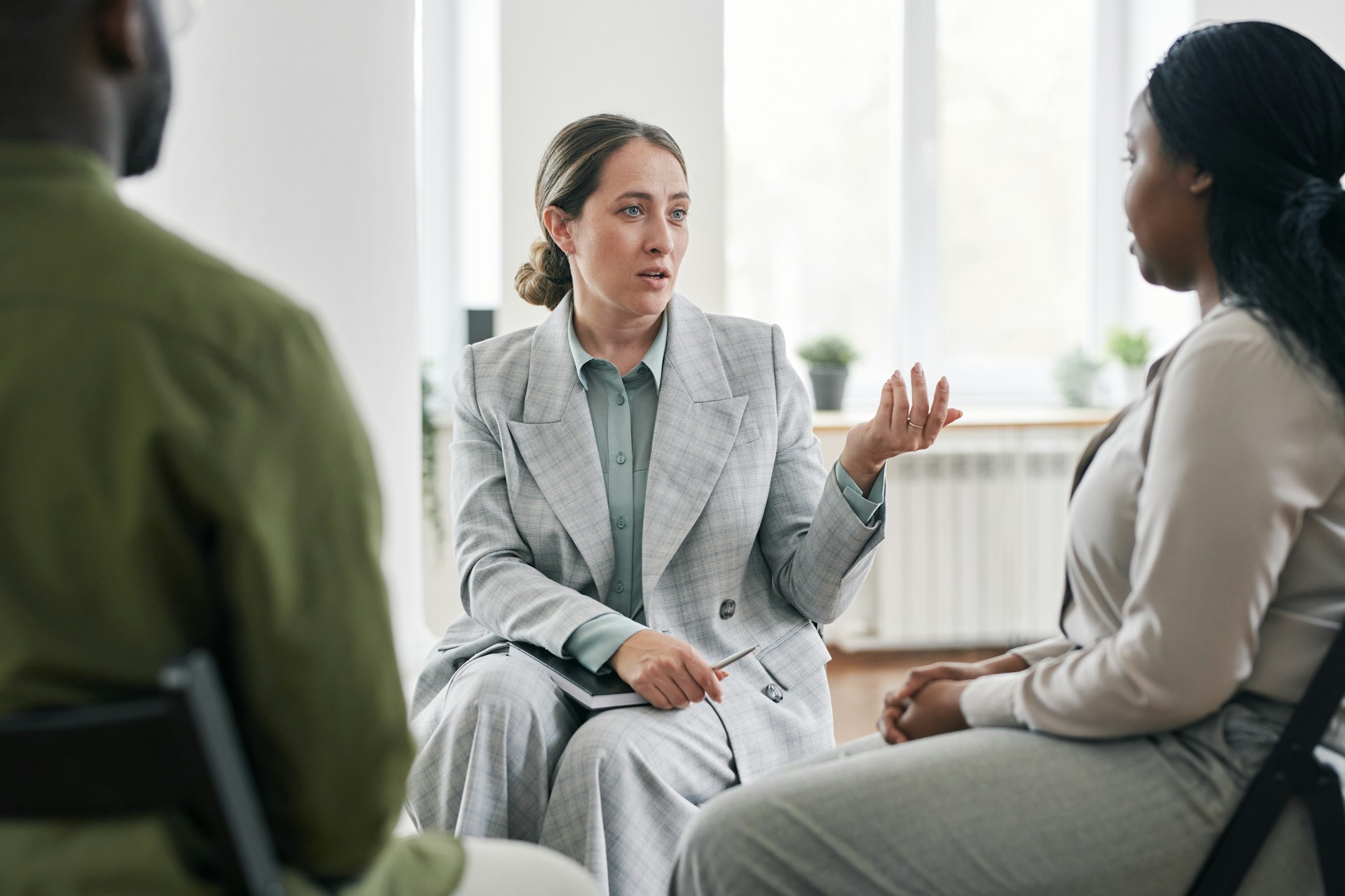 A woman sitting in a circle with other work colleagues, talking about burn out in the workplace and how to prevent it.