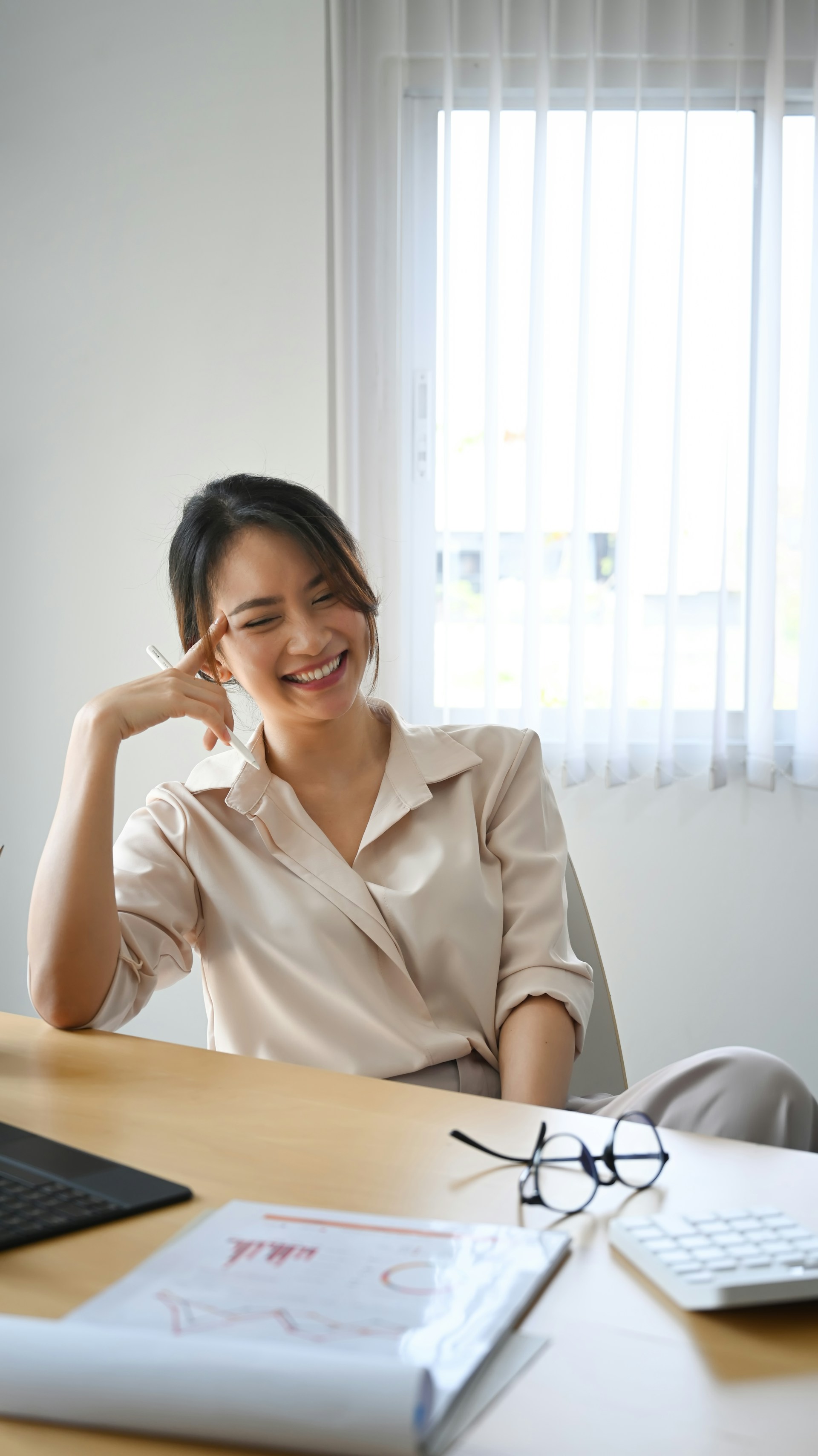 A woman smiling and laughing at her desk, feeling good about her role and wellbeing in her workplace.