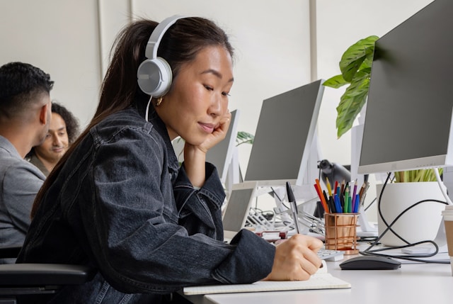 A woman sitting at her desk, writing notes about the course she's taking from the Balanced Elite about burn out prevention in the workplace.