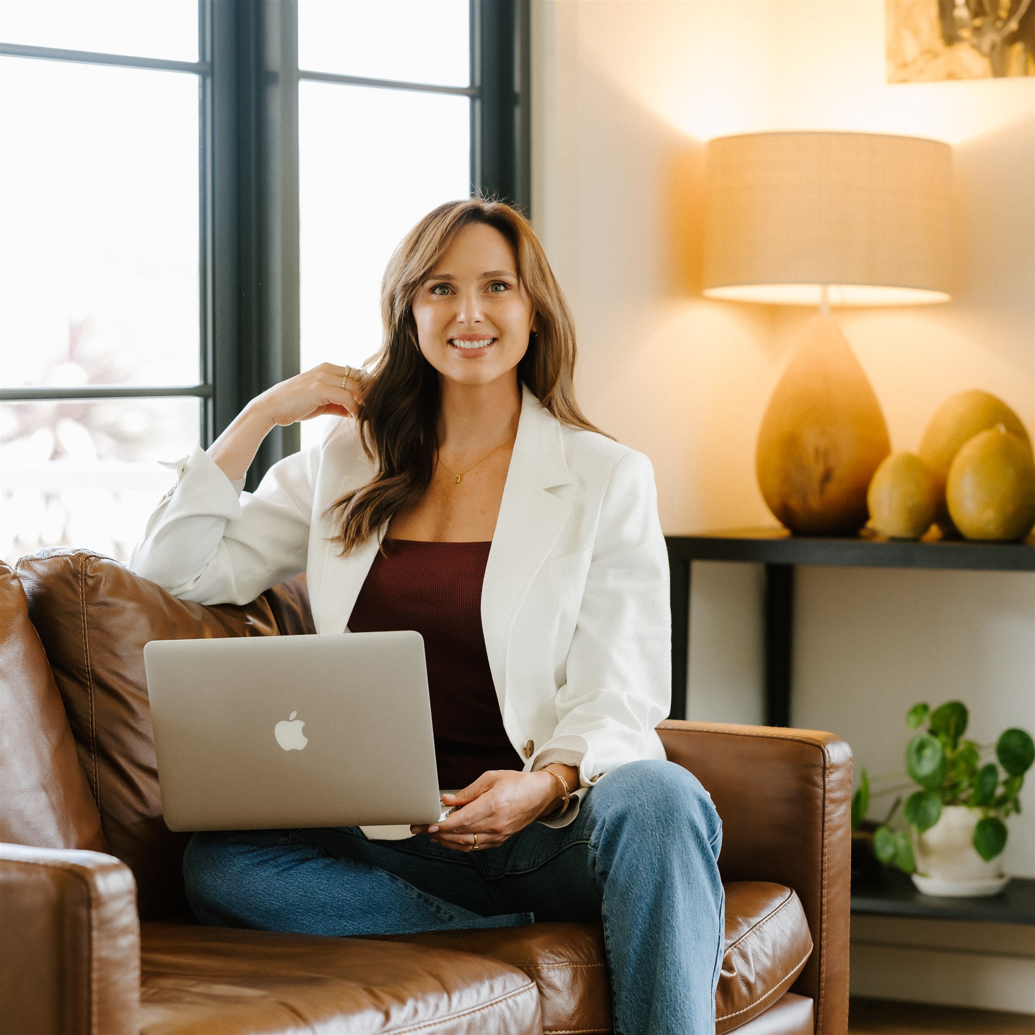 An image of Lucy Quick from The Balanced Elite, sitting with her laptop working on workplace wellbeing.