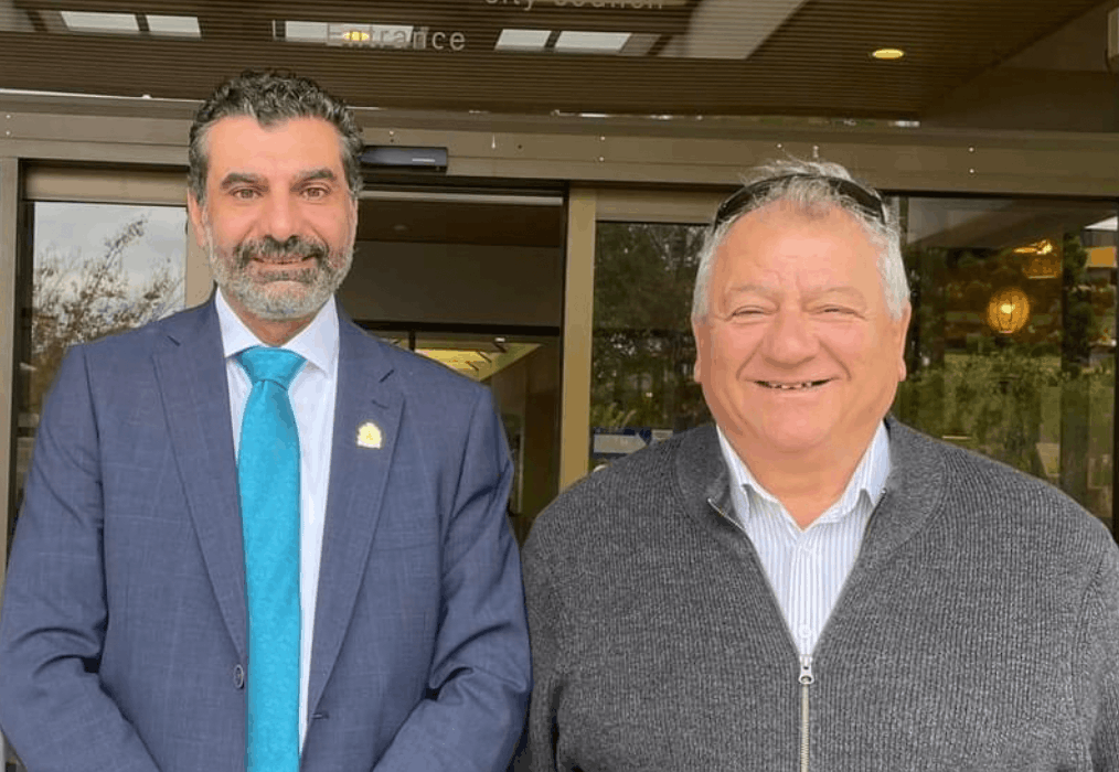 Dr George Greiss standing with another man outside a building entrance, both smiling.