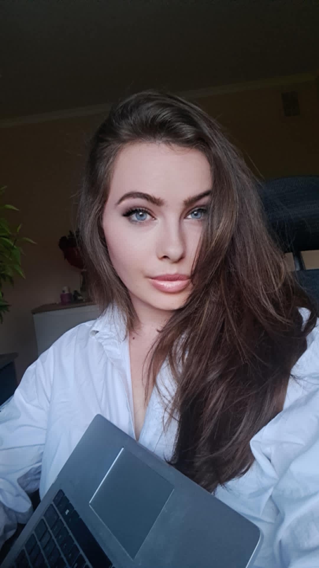 Kobieta, założycielka strony, brązowe długie włosy, niebieskie oczy, z laptopem w pozycji siedzącej w białej koszuli