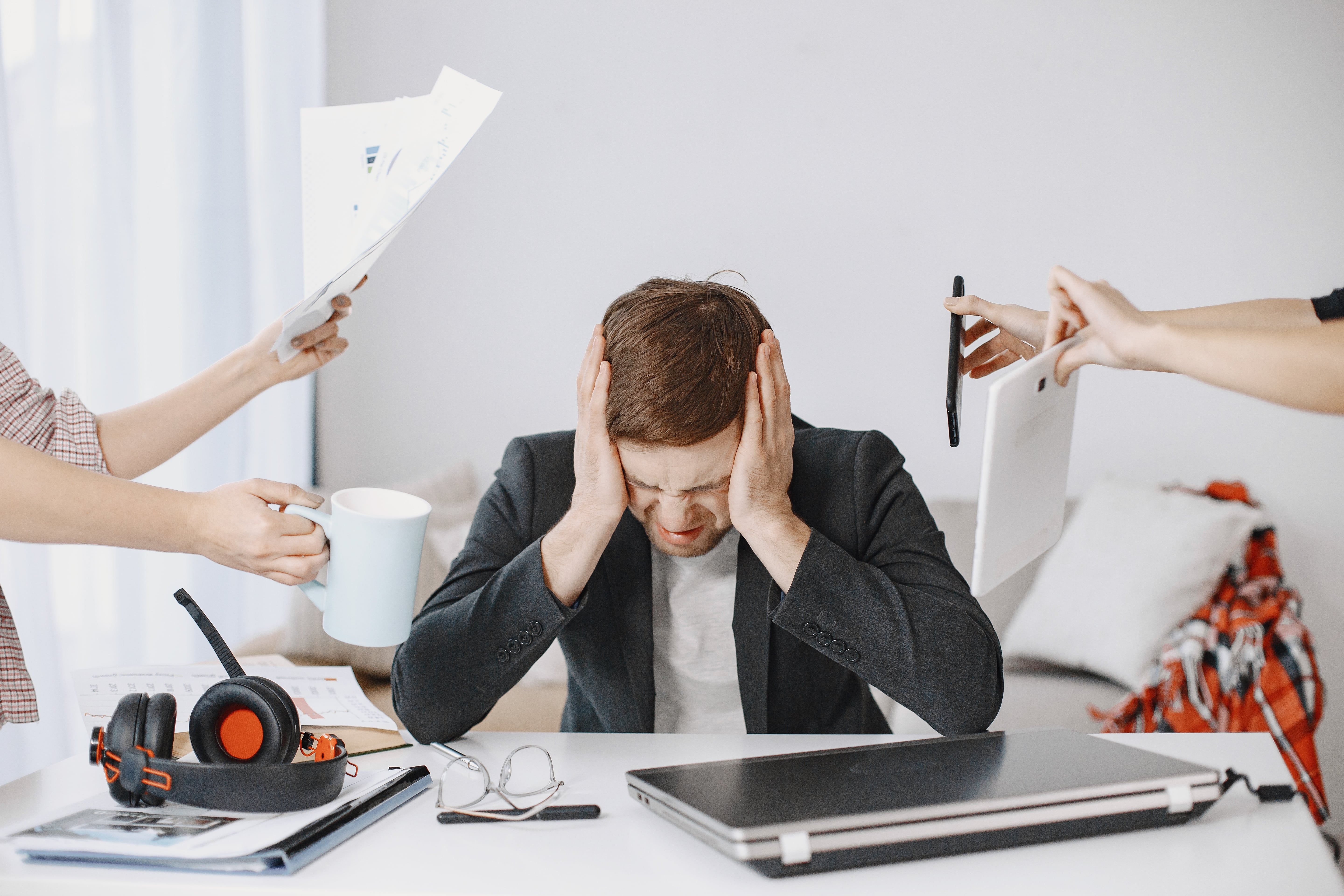 Man at his work station is stressed out from many people demanding his attention