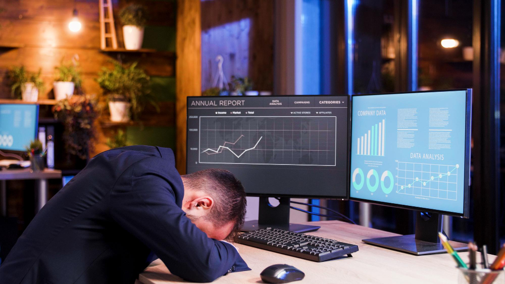 Business sleeping in front of his desktop tired of looking at loss reports