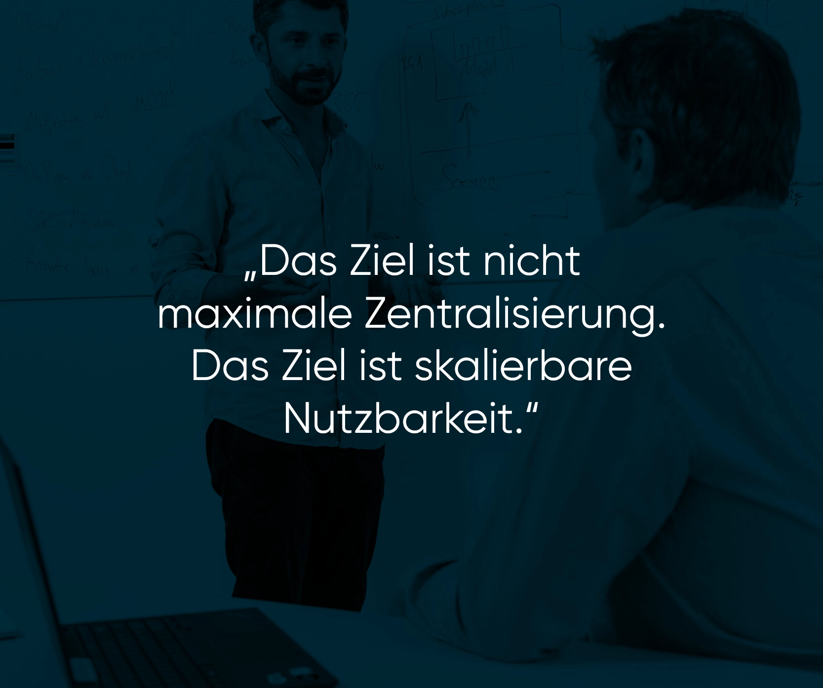 weißer Text auf blau eingefärbten Bild mit zwei männlichen Personen, die miteinander sprechen: „Das Ziel ist nicht maximale Zentralisierung. Das Ziel ist skalierbare Nutzbarkeit.“