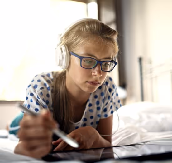 Young Girl Wearing Headphones Doing Homework