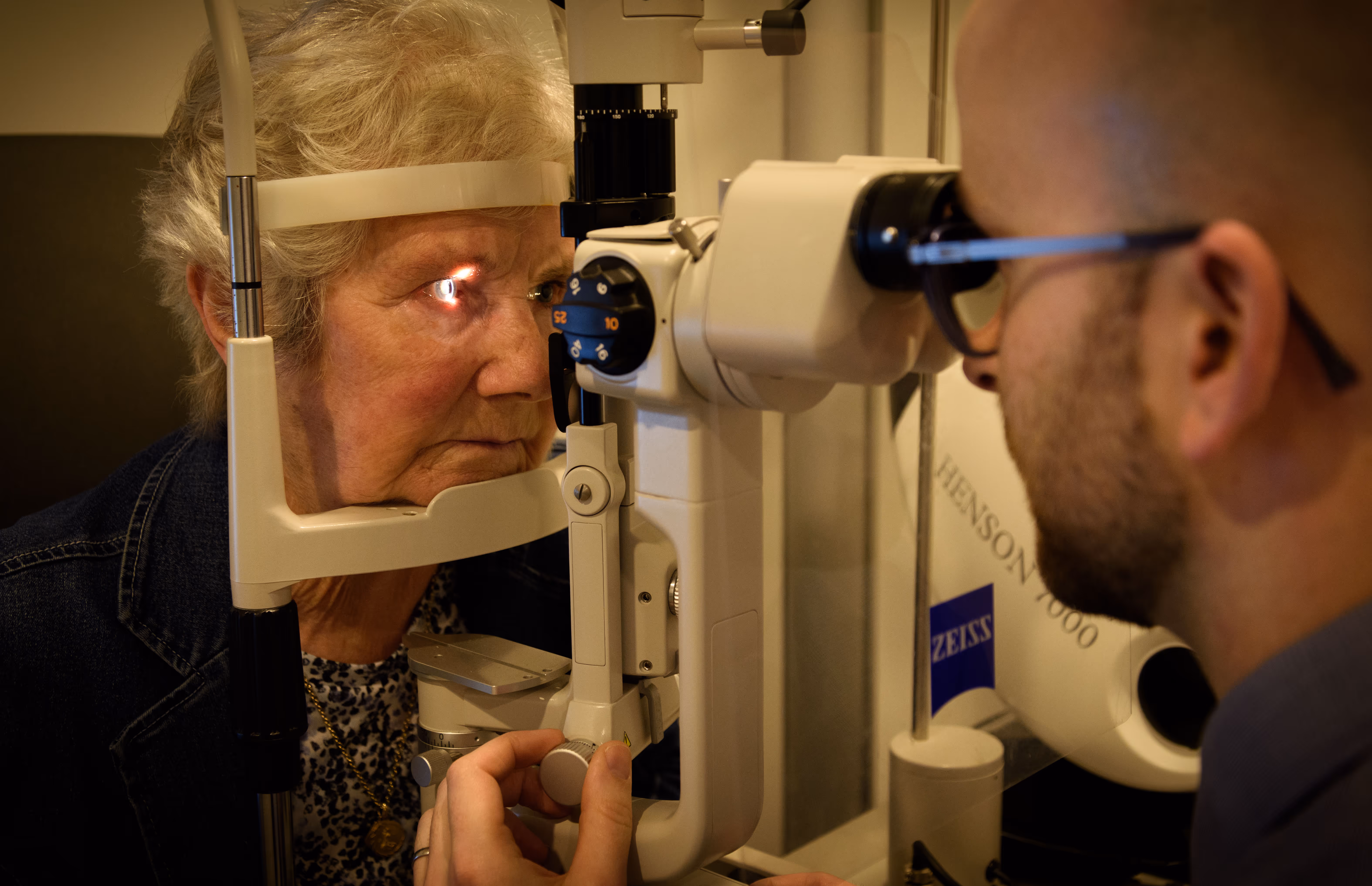 Elderly patient receiving eye exam with optical equipment