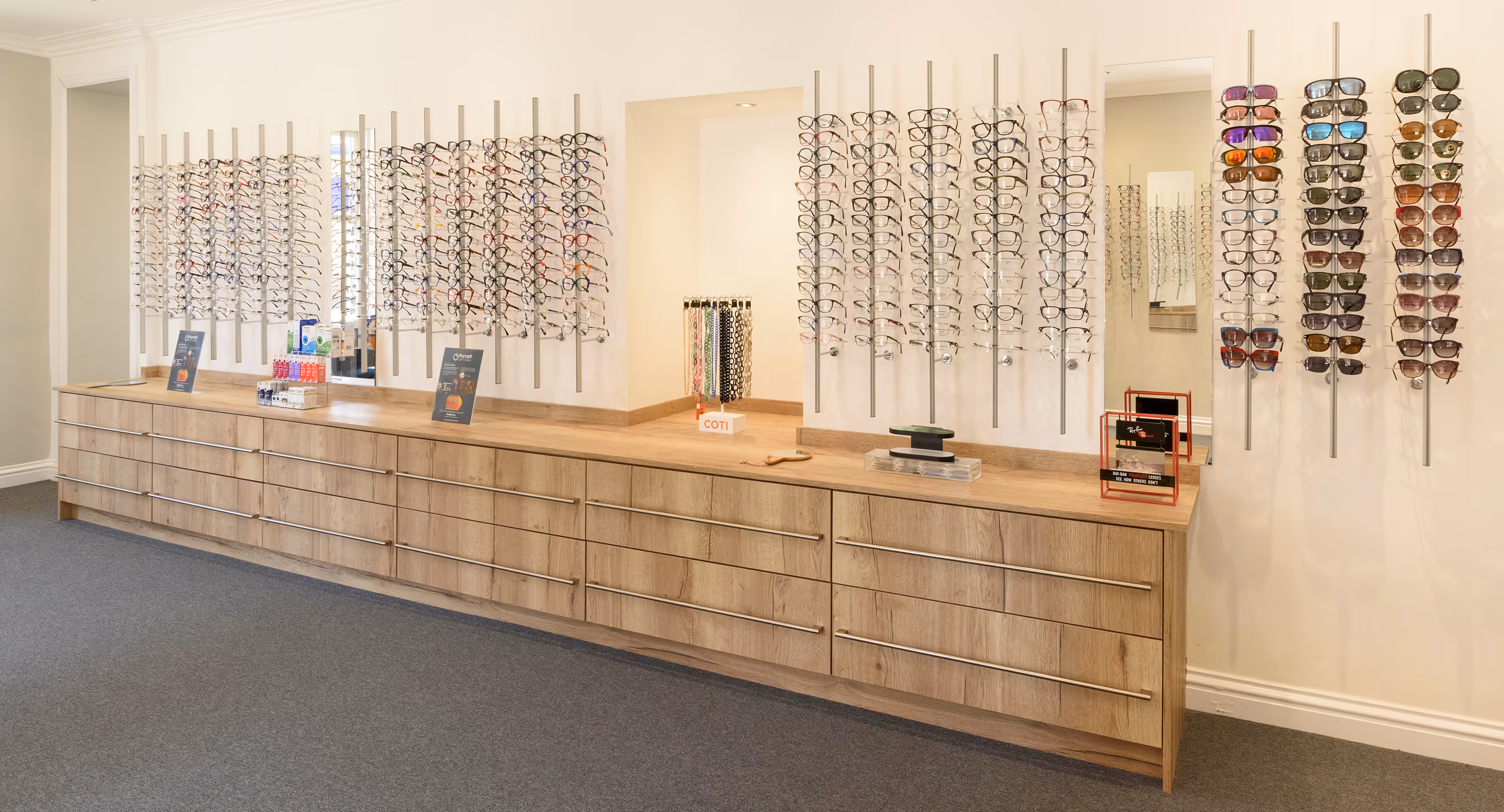 Eyeglass store with wooden counter and multiple displays of glasses and sunglasses