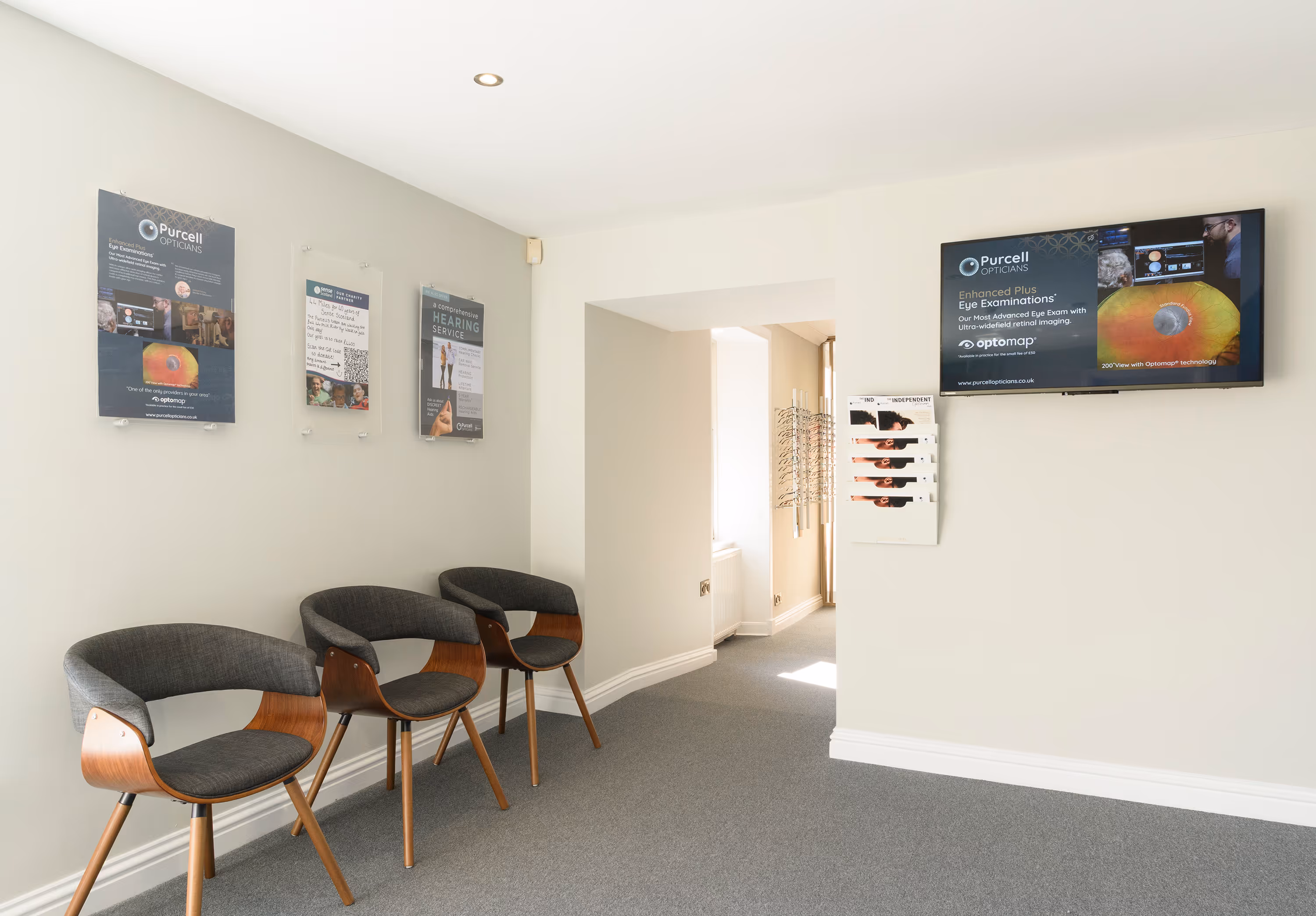 Purcell Opticians waiting room with gray chairs and eye examination posters