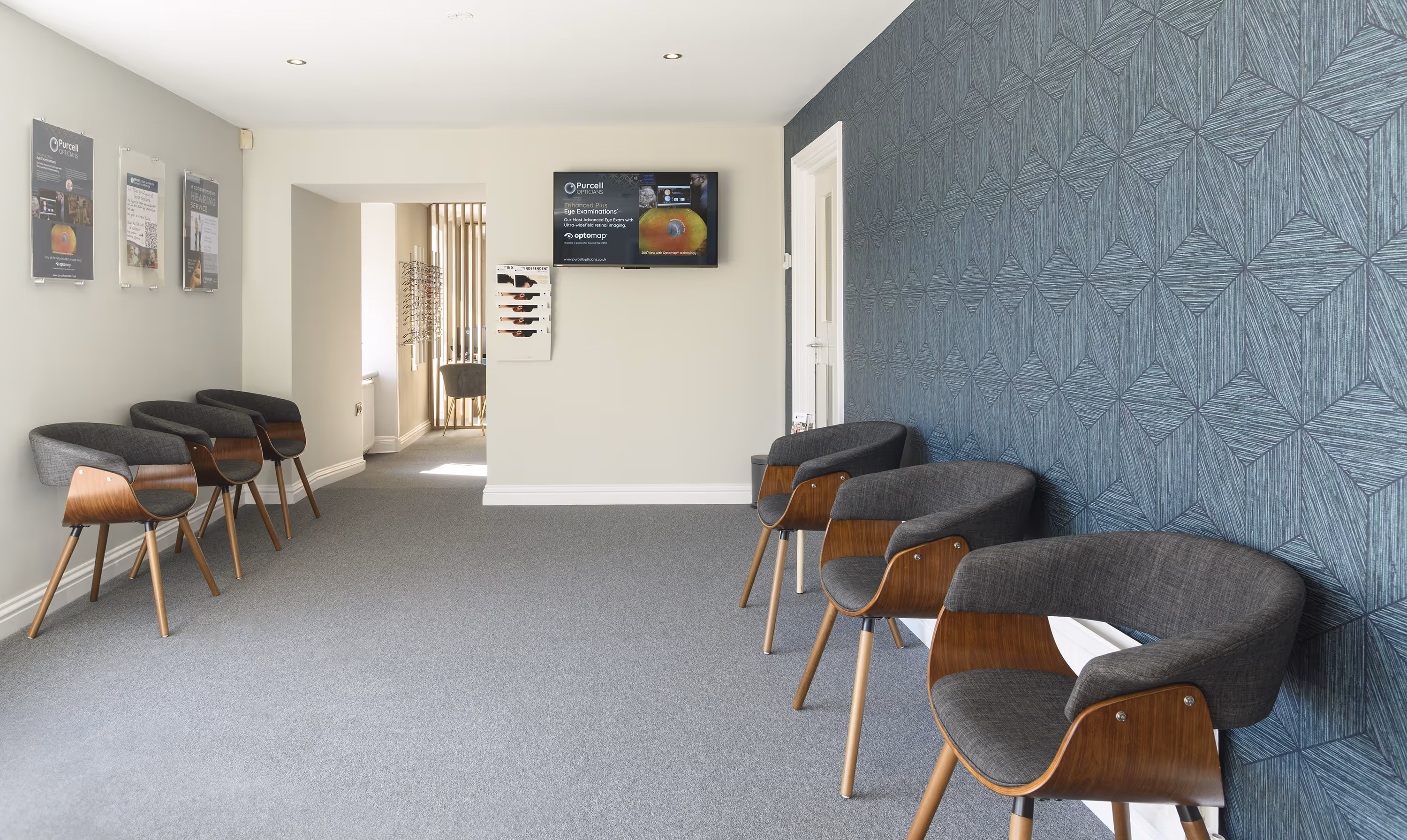 Modern eye clinic waiting room with gray chairs and display screen