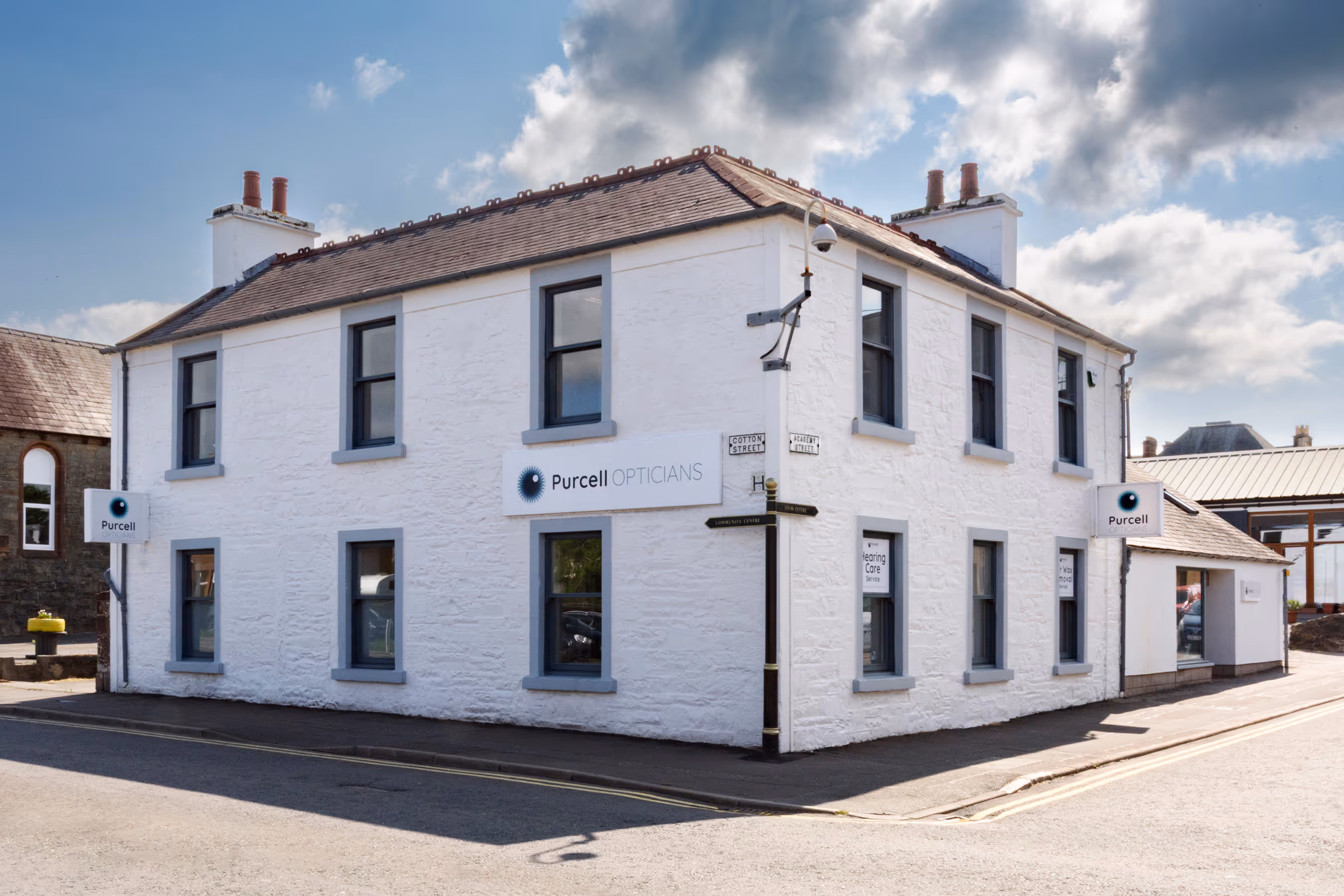 White corner building housing Purcell Opticians on a sunny day