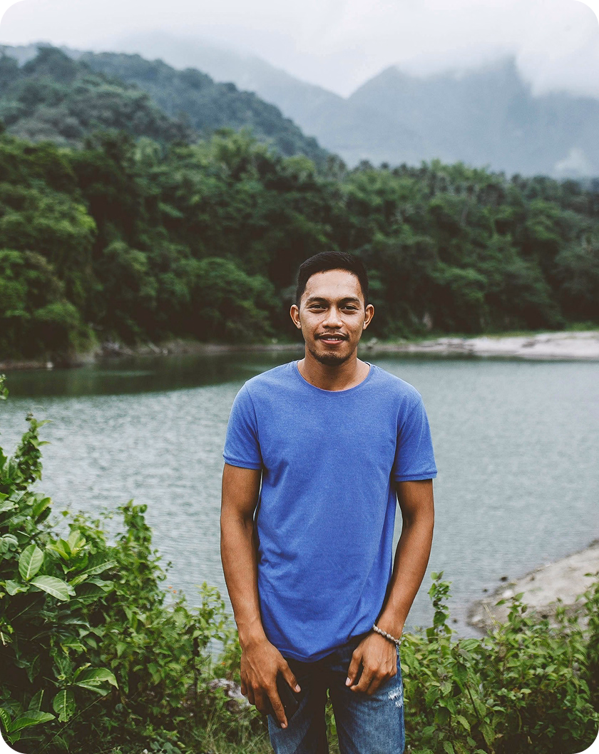 A man on a hike in front of a waterfall