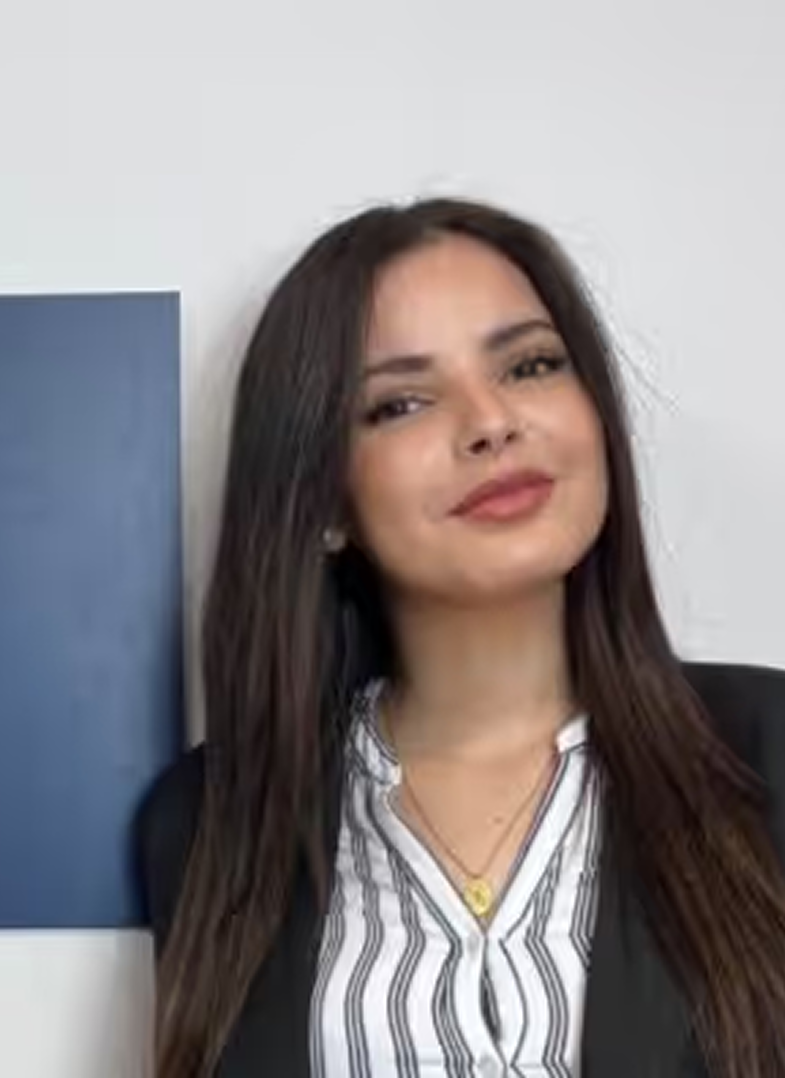 Portrait d'une femme souriante aux cheveux longs et port d'un chemisier rayé avec un blazer noir.