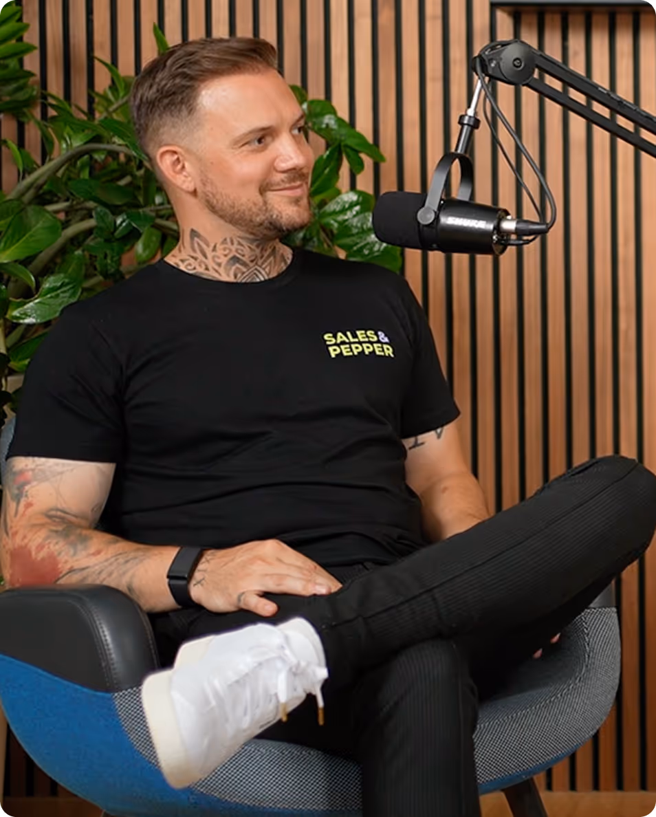 Mann mit Tattoos im Podcast-Studio mit Mikrofon und Pflanze