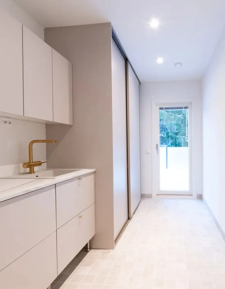 Valkoinen moderni kodinhoitohuone, jossa on pyykinpesukone ja kuivausrumpu.