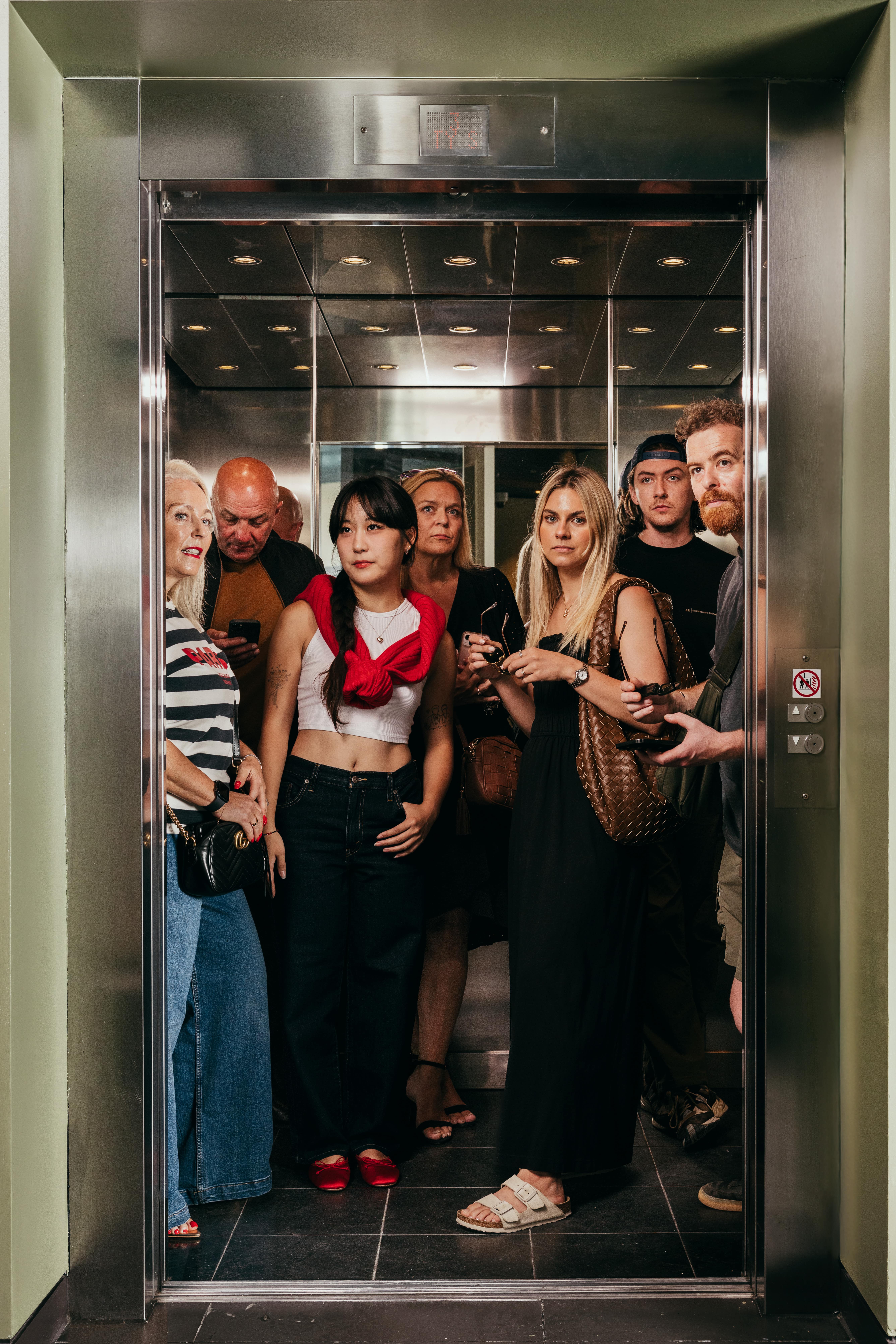 Crowded elevator full of different people.
