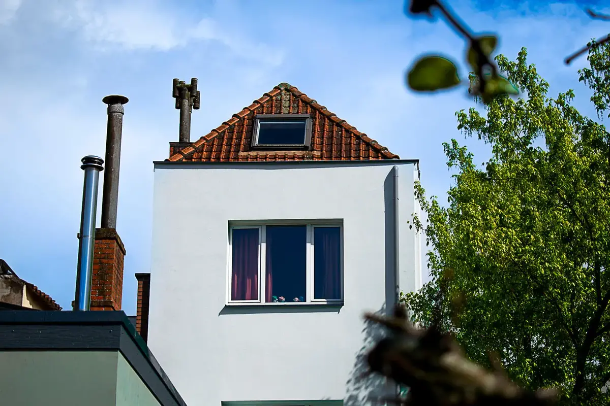 Woning met witte crepi-gevel en rood pannendak, beschermd met Energy Protect voor duurzame isolatie en langdurige gevelbescherming.