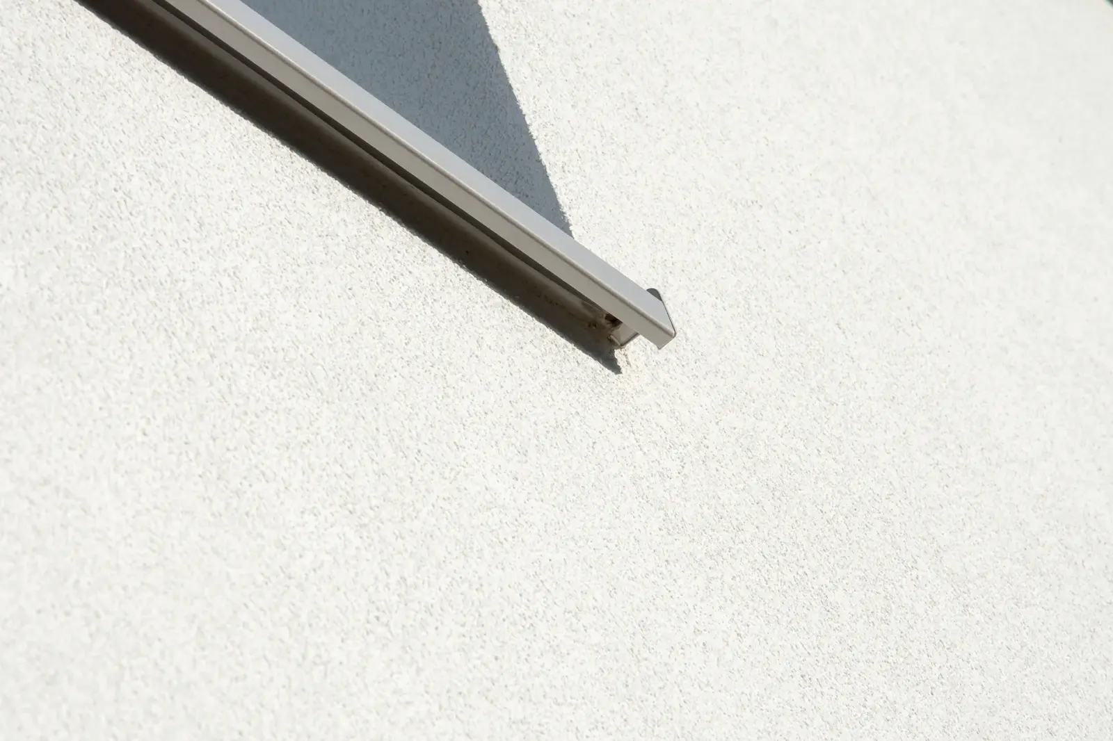 Close-up van witte crepi-gevel met aluminium raamprofiel, strakke afwerking en duurzame isolatie door Energy Protect.