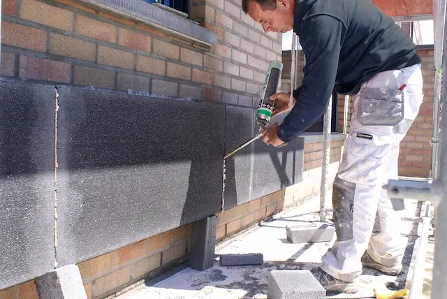 Isolatiespecialist brengt purschuim aan tussen harde gevelisolatieplaten voor naadloze thermische bescherming en energiebesparing.
