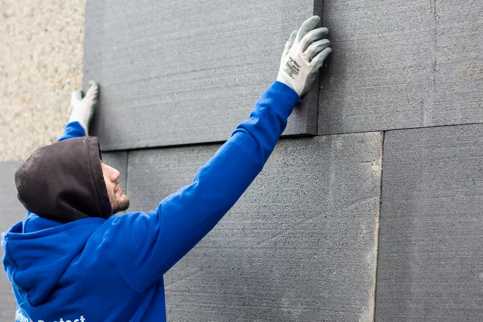 Isolatiespecialist plaatst zorgvuldig grijze gevelisolatieplaten voor optimale warmtebesparing en energie-efficiëntie.
