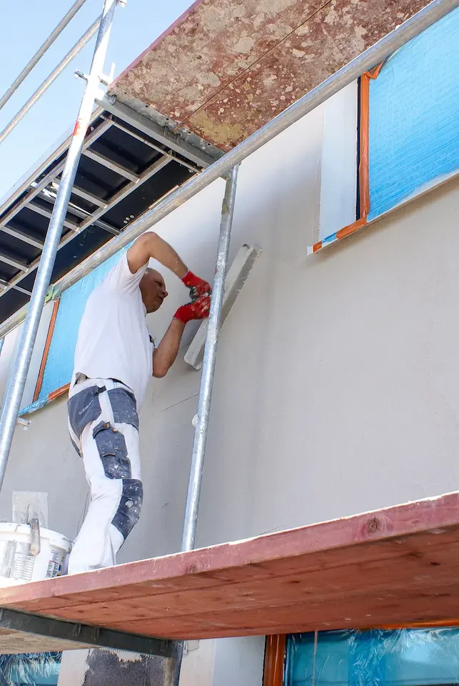 Bouwvakker brengt buitengevelpleister aan over gevelisolatie voor energiezuinige woningrenovatie.