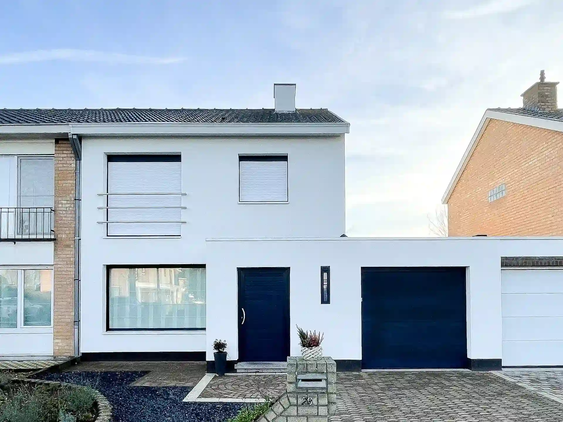 Energiezuinige gerenoveerde woning met witte gevelisolatie en moderne zwarte accenten.