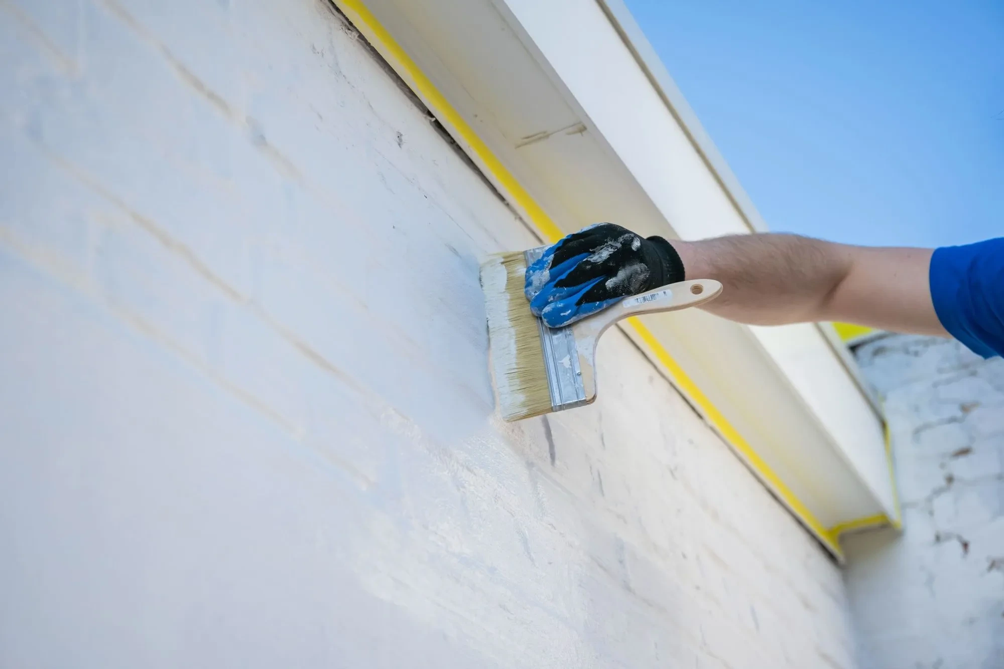 Vakman op ladder brengt witte kalei-afwerking aan op bakstenen gevel met Energy Protect voor duurzame isolatie en weerbestendige bescherming.