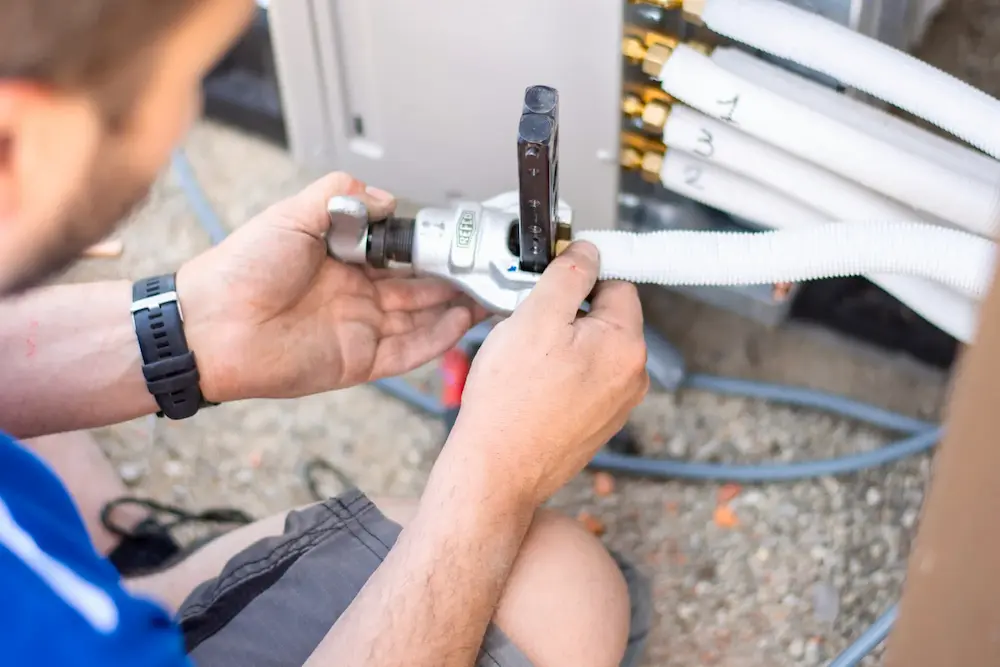 Monteur van Energy Protect sluit koelmiddelleidingen aan tijdens installatie van energiezuinige LG split-airco.