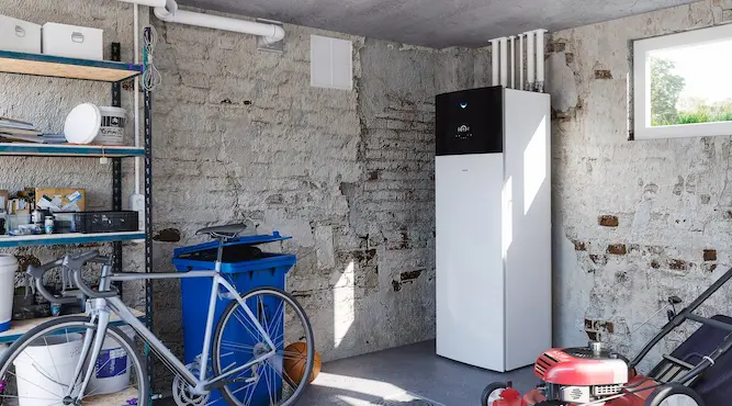 Een witte LG lucht-waterwarmtepomp van Energy Protect staat in een garage tegen een  stenen muur.