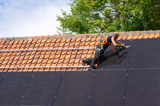 Een dakwerker die twee rijen zwarte zonnepanelen installeert op een plat dak door Energy Protect.