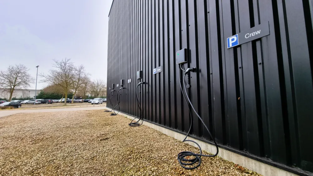 Rij laadpalen langs zwarte gevel bij parkeerplaatsen voor elektrische auto’s, duurzame oplossing van Energy Protect