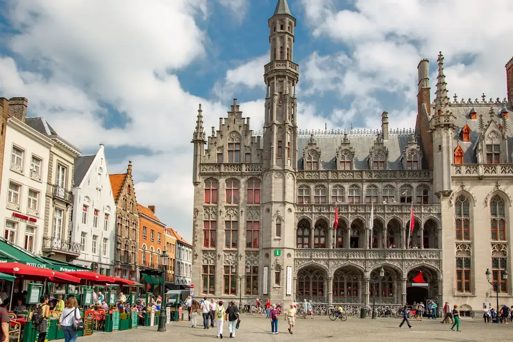 Historisch stadhuis van Brugge op de Markt met gotische gevel, toeristen en terrasjes in West-Vlaanderen.
