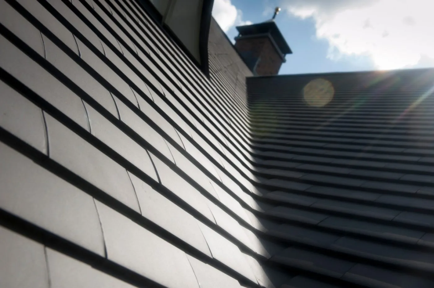 Strak gelegd leien dak met zonlichtreflectie, duurzame en weerbestendige dakbedekking voor energiezuinige gebouwen.