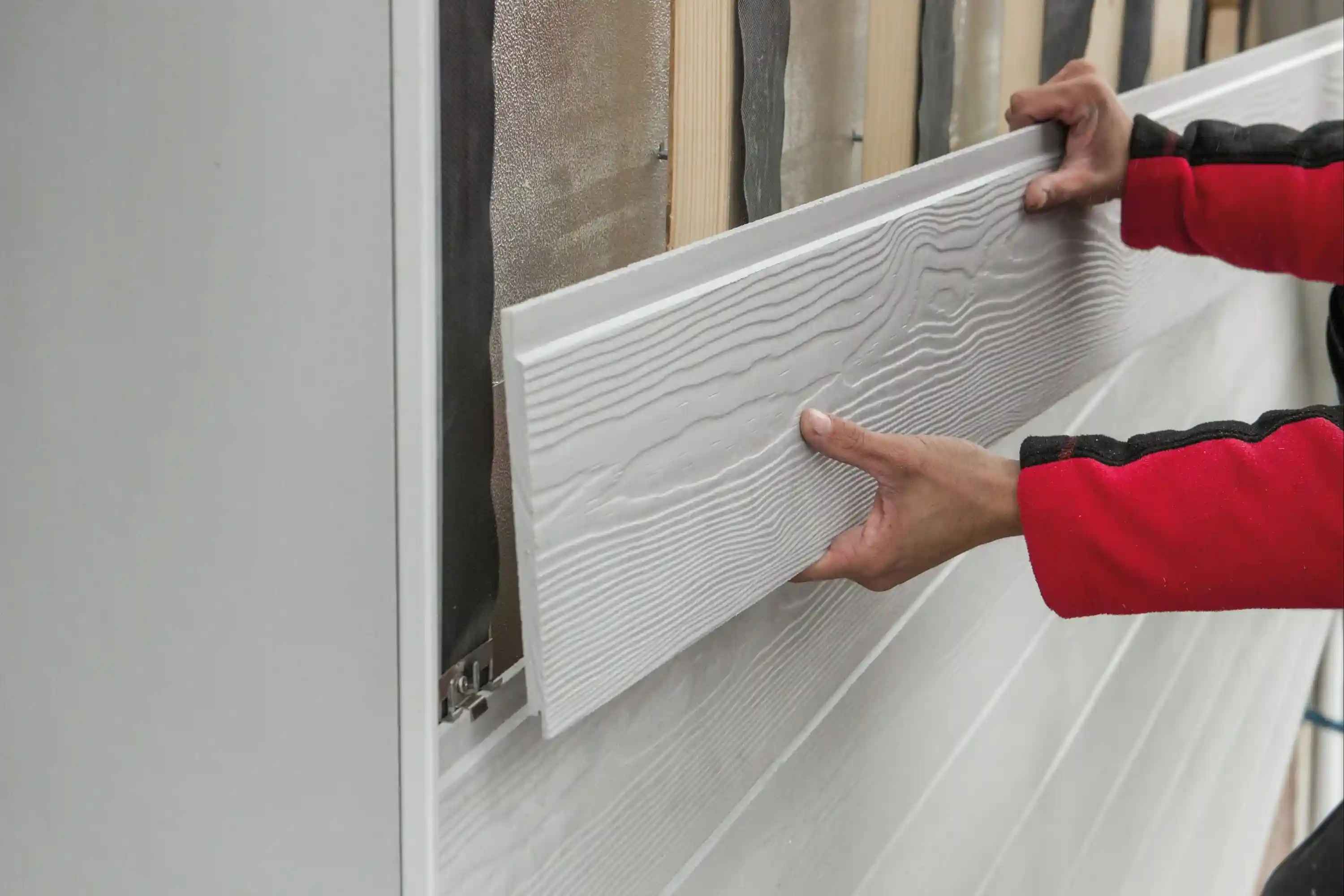 Detailopname van het plaatsen van sidings met een zichtbare houtnerfstructuur door Energy Protect.