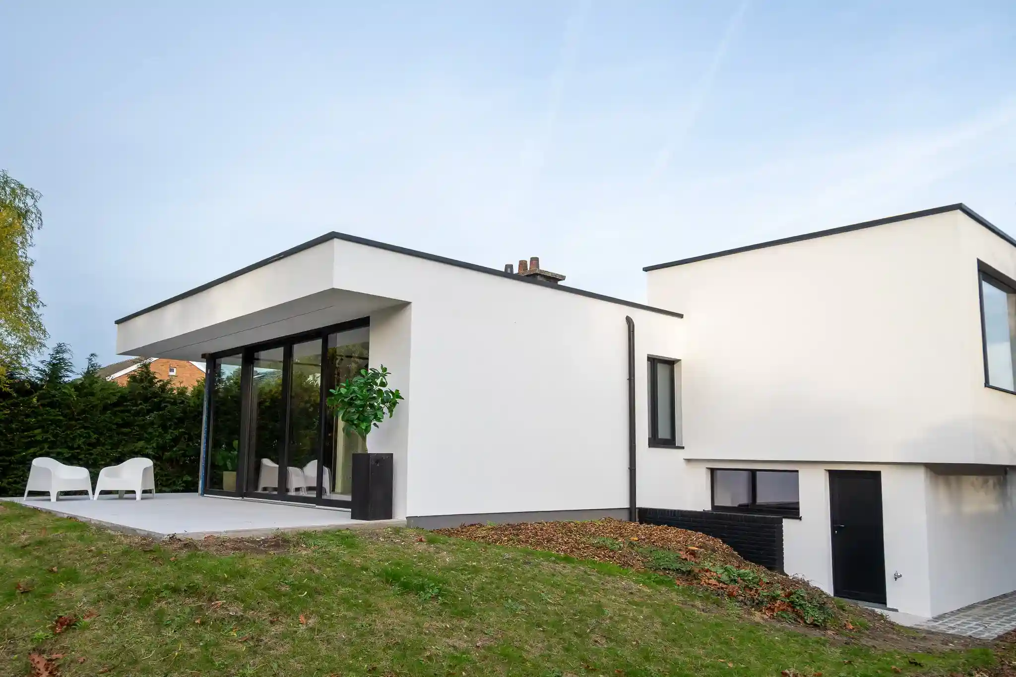 Achtergevel van een moderne woning in witte crepi met groot schuifraam, afgewerkt door Energy Protect.