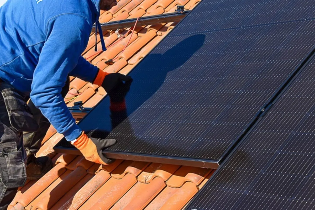 Installateur plaatst zonnepanelen op een pannendak