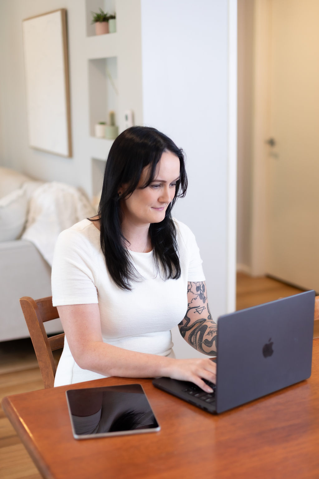 Alice Xerri, Founder and Fractional Content Lead, Freelance Copywriter for Finance, B2B Tech and SaaS, working on laptop with iPad sat next to her.