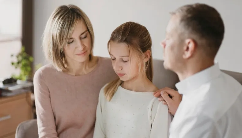 Parents réconfortant leur enfant, illustrant la protection de la famille en cas d'imprévu.