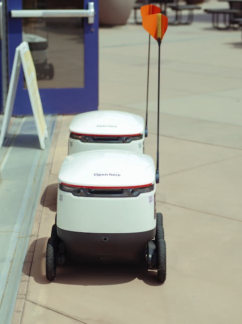 High angle view of two autonomous delivery robots positioned outdoors, showcasing modern technology.. Photo by Kindel Media on Pexels
