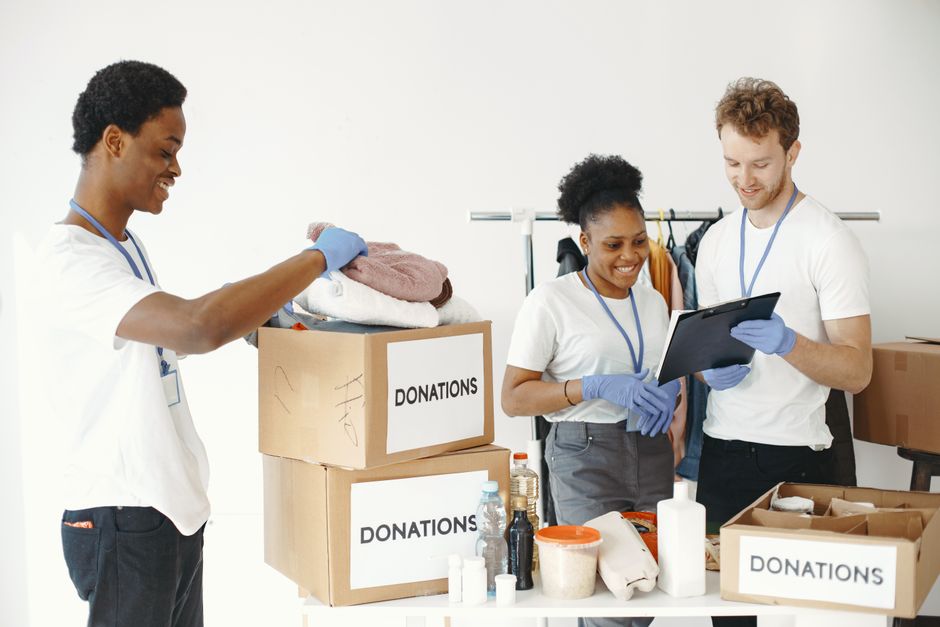 Dedicated volunteers sorting donation boxes indoors for community support.. Photo by Gustavo Fring on Pexels